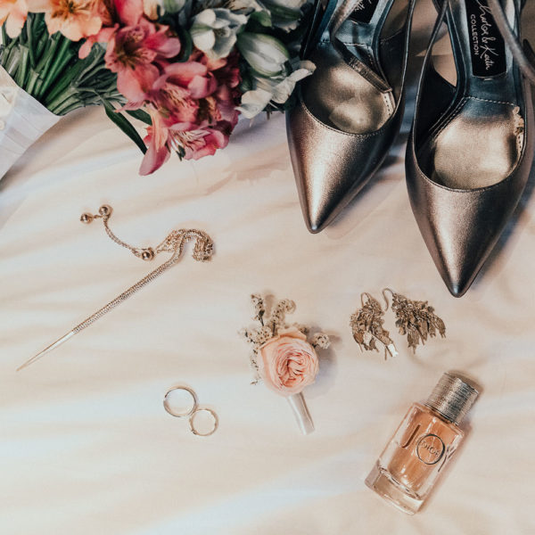 Wedding details layout made by photographer in Amsterdam shows bridal shoes, flower bouquet, rings, buttonhole and perfume.