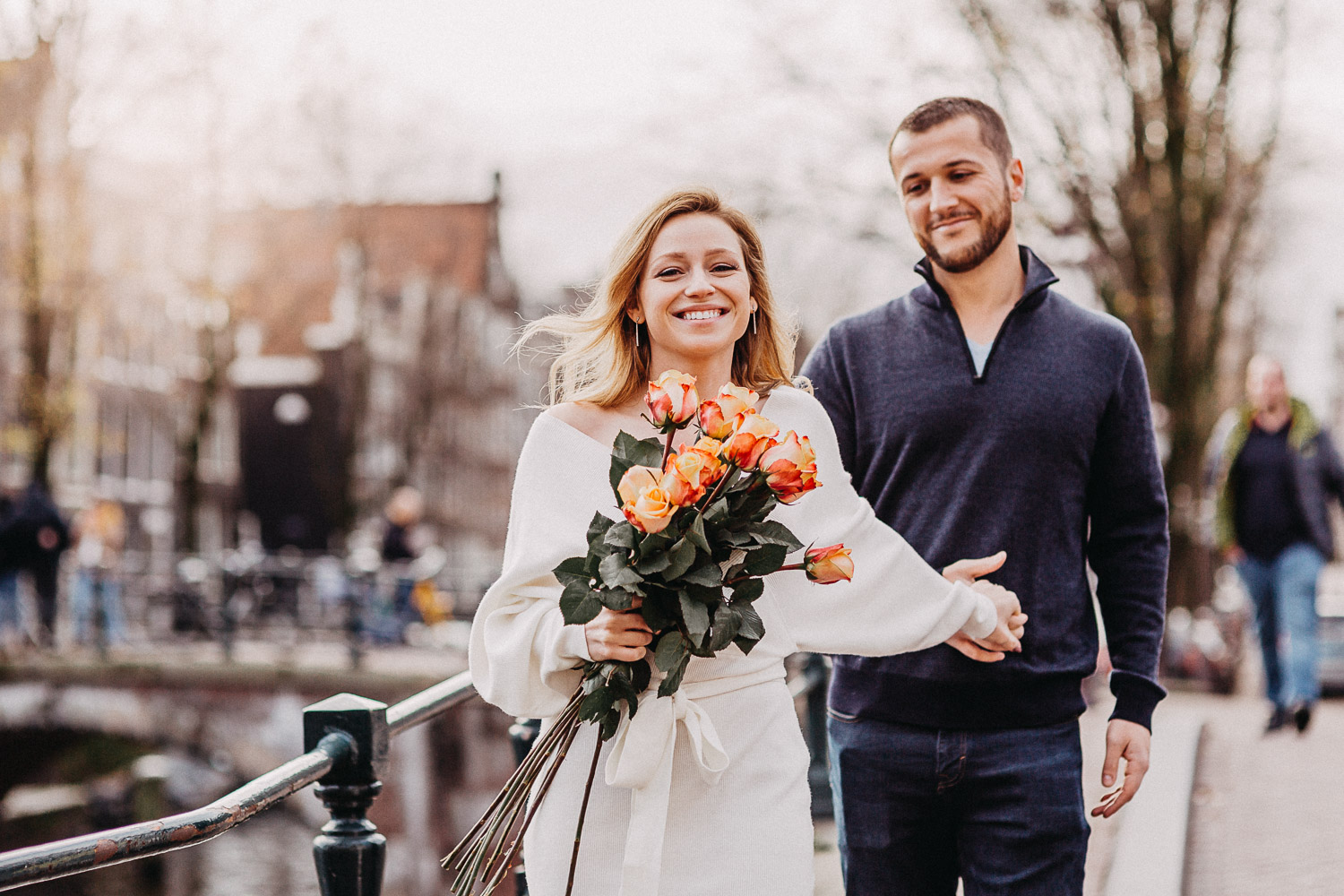 Happy couple smiling and holding hands and walking on the street on autumn wedding photoshoot by wedding photographer in Amsterdam