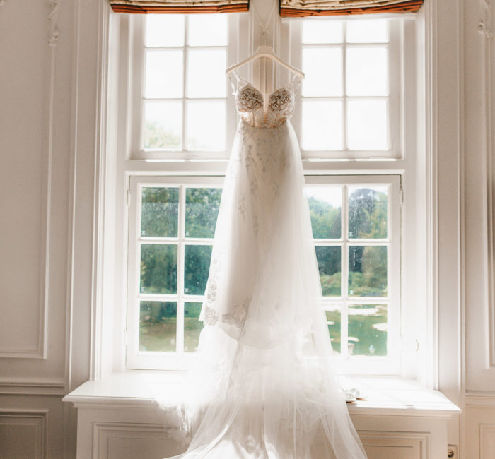 Hanging wedding bridal dress on the window. Morning of the bride and wedding photoshoot in the Netherlands.