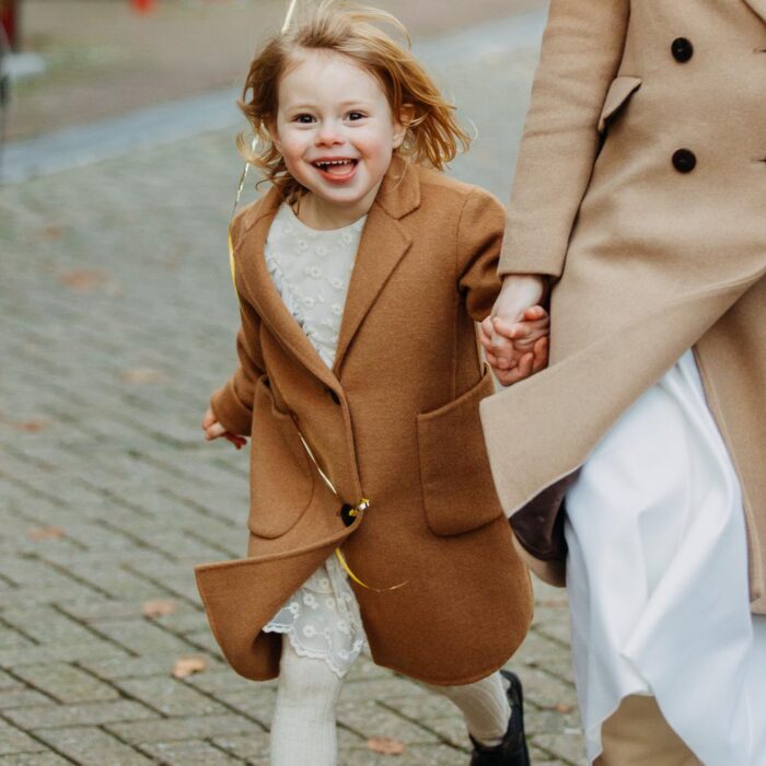 Smiling little girl holding her mother's hand during a family photoshoot in Amsterdam by an Amsterdam photographer