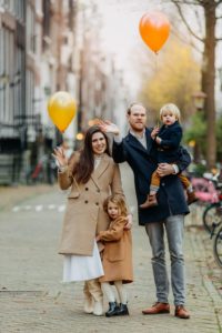 Family photographer in Amsterdam captures a couple with children with balloons, staying on one of the street of Amsterdam