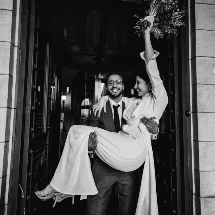 Groom carrying the bride outside a wedding venue captured by a professional photographer in Amsterdam