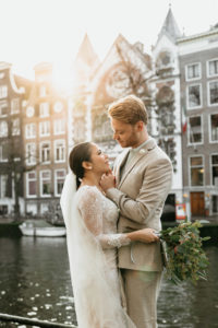 Wedding couple in love during their wedding photoshoot in Amsterdam. The groom touches her face and smiles