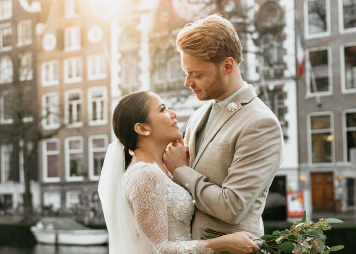 Wedding couple in love during their wedding photoshoot in Amsterdam. The groom touches her face and smiles