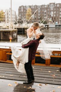 Couple getting married in Amsterdam, groom lifts up the bride and look at her. Photographer caputres their wedding photoshoot in Amsterdam