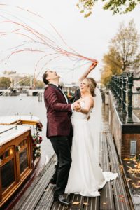 Happy couple launching streamers confetti at their wedding photoshoot in Amsterdam. how to getting married in Amsterdam click on this photo.