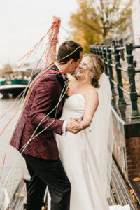 Happy couple thrown confetti and smiling. Photographer captures the moments of their wedding photoshoot in Amsterdam. If you need to learn how to getting married in Amsterdam read this article.