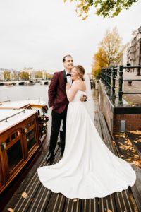 Happy couple stays on the pier while the photoshoot and their Amsterdam elopement. How to getting married in Amsterdam to click on the photo.