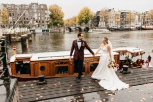 Bride and groom walking down the canal of Amsterdam because they decided to Getting married in Amsterdam and travelled for their Amsterdam elopement