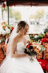 Beautiful portrait of the bride, sitting on the boat during her wedding in Amsterdam. Photographer captures moments during their wedding photoshoot in Amsterdam.