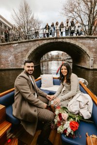 Couple sitting on the boat after their boat proposal in Amsterdam. Their friends are on the background