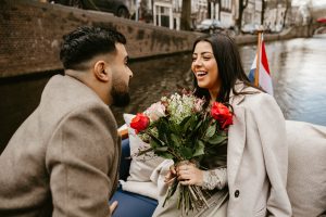 Private boat proposal Amsterdam, the guy pops a question and give flowers to his girlfriend