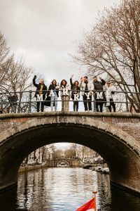 Amsterdam proposal on a boat. Group of people staying on the bridge and holding letters Marry me