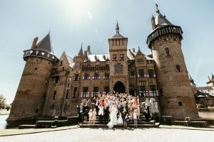 Trouwen in Kasteel de Haar is de mooiste trouwlocatie. all the guests make group picture standing in front of Castle de Haar