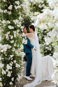 Groom lifts up his bride in a garden surrounded by beautiful flowers. Couple poses for a wedding photoshoot in Kasteel de Haar.