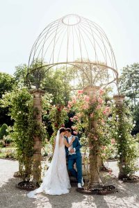 A couple standing in a garden surrounded by beautiful flowers for their bruiloft in Kasteel de Haar.