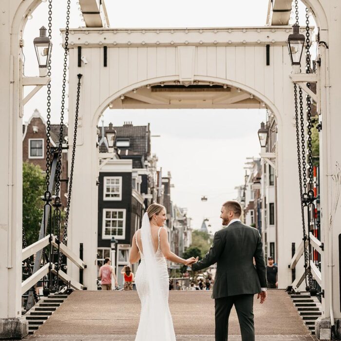 Bride and groom walking across the Skinny Bridge during a wedding photoshoot in Amsterdam by a professional photographer