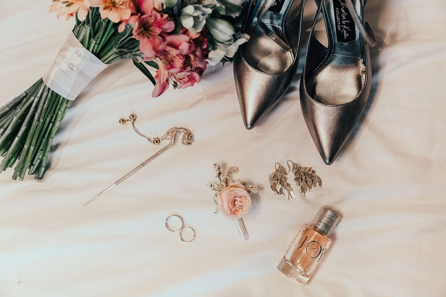Wedding details layout made by photographer in Amsterdam shows bridal shoes, flower bouquet, rings, buttonhole and perfume.